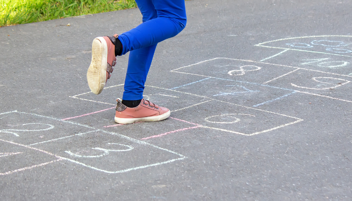 Kuvassa lapsi hyppää ruutua ulkona.
